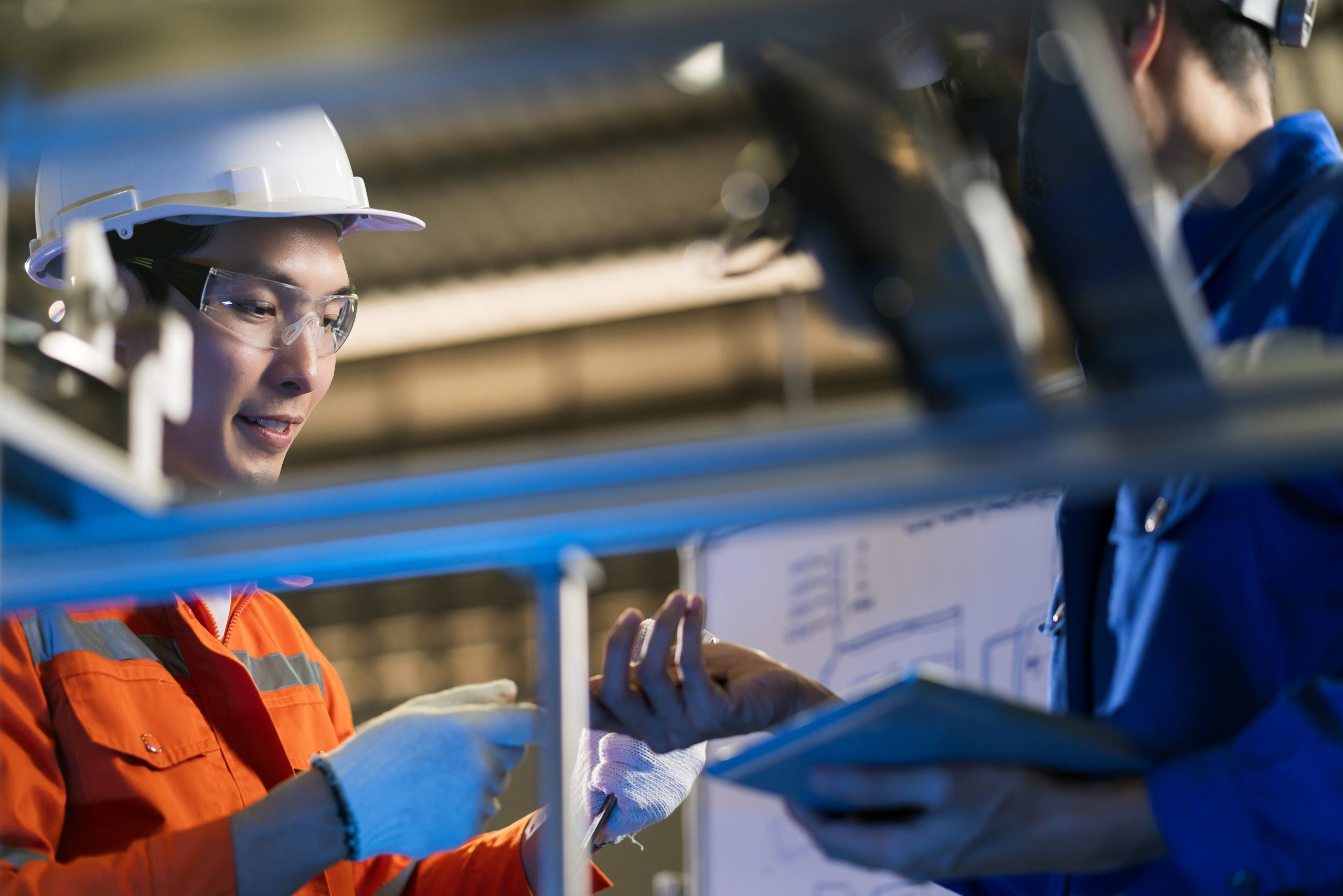Male Asian engineer professional having a discussion standing by the machine in the factory ,two asian coworker brainstorm explaining and solves the process curcuit mother board of the machine