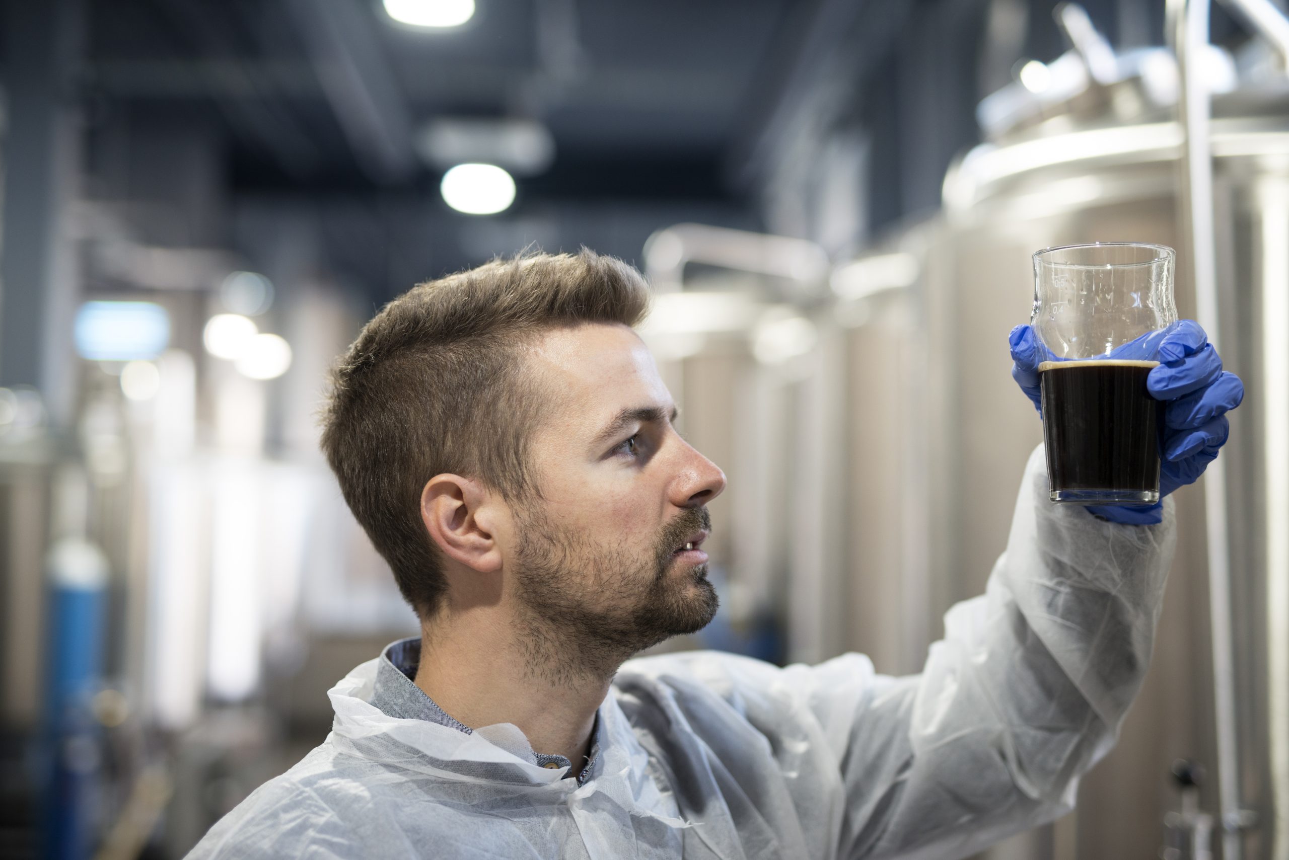 Technologist in brewery checking beer quality.