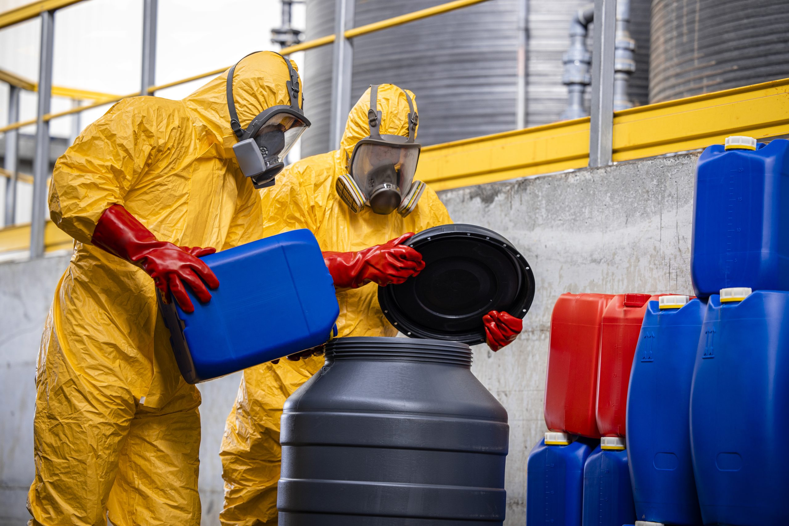 Chemical plant workers in hazmat suit mixing chemicals and manufacturing acids for heavy industry.
